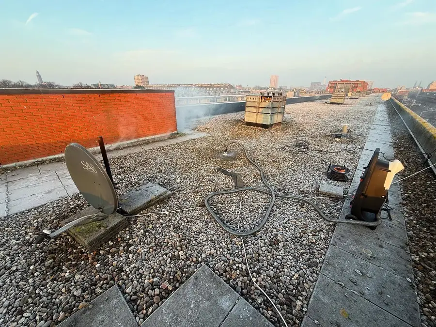 De rookmachine op een grinddak; op de achtergrond komt de rook al naar buiten