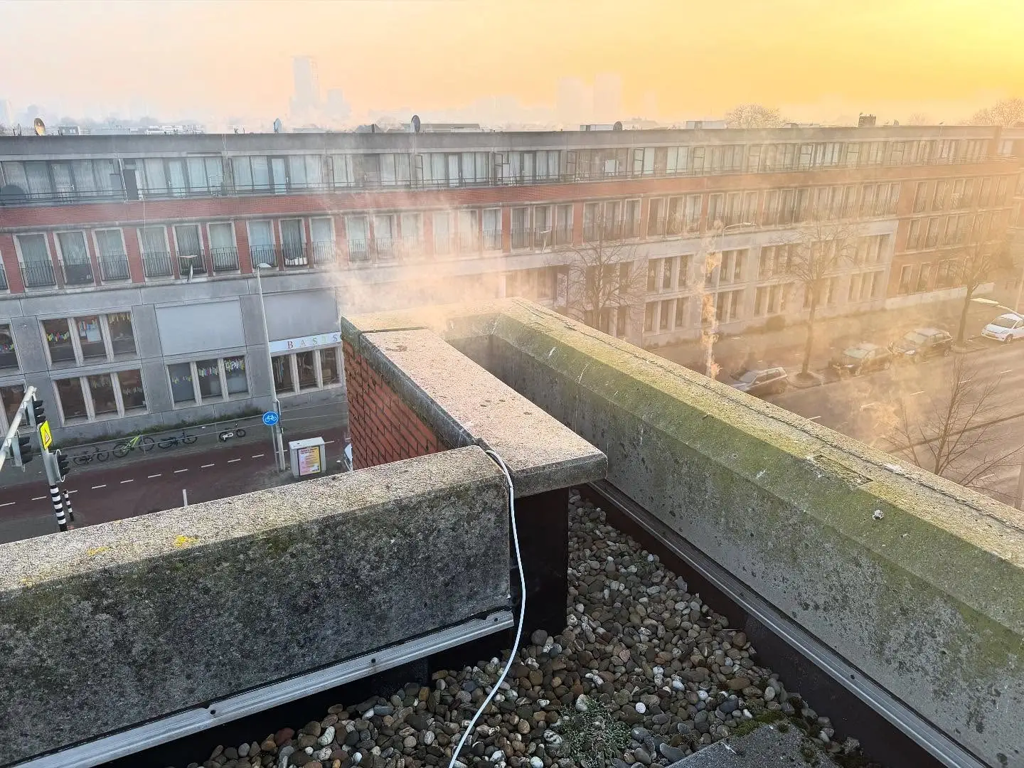 Rook komt naar buiten bij de dakrand van een appartementengebouw tijdens een rookproef