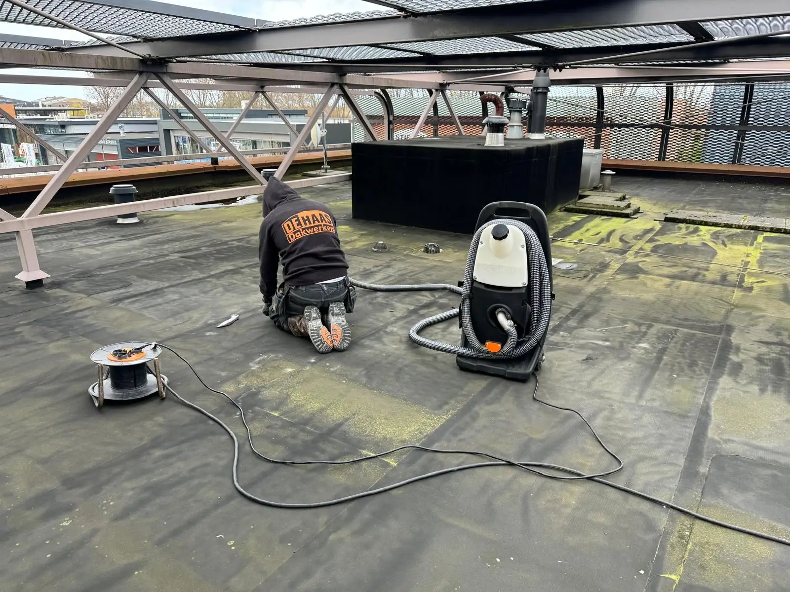 Medewerker van De Haas Dakwerken spoort een lekkage op met een rookmachine op een plat dak
